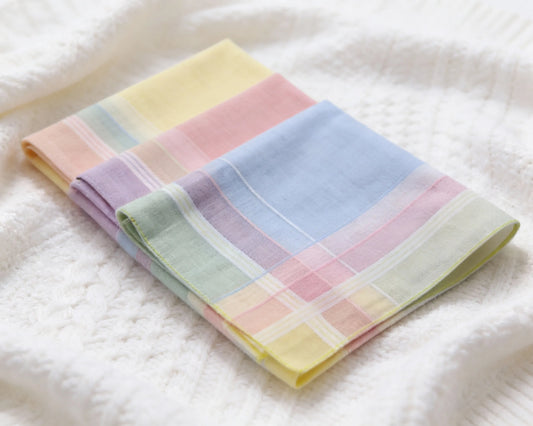 Set of pastel-colored folded hanky on a white textured surface