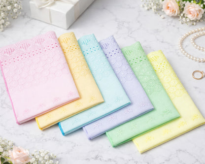 Set of pastel-colored handkerchiefs on a light surface with flowers and jewelry in the background.