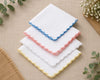 Set of white handkerchiefs with colorful scalloped edges on a beige fabric background.
