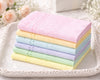 Stack of pastel-colored textured towels on a decorative tray with floral background