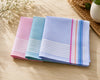 Three folded handkerchiefs in pink, blue, and multicolor on a wooden surface.