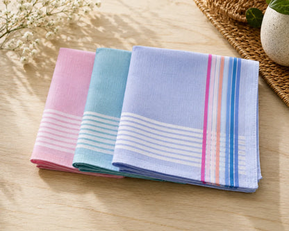 Three folded handkerchiefs in pink, blue, and multicolor on a wooden surface.