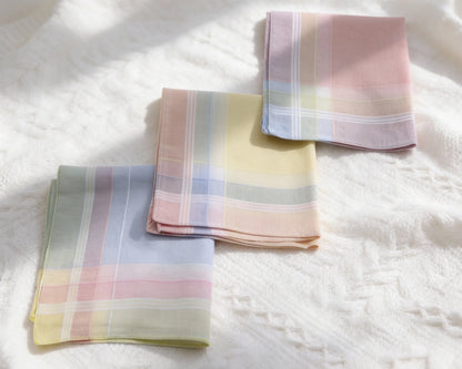 Three plaid hanky in pastel colors on a white textured surface