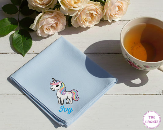A serenity blue cotton handkerchief personalized with the name "Ivy" and a vibrant multi-color embroidered magical unicorn.