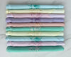 Stack of folded fabric swatches in pastel colors with floral patterns on a white background
