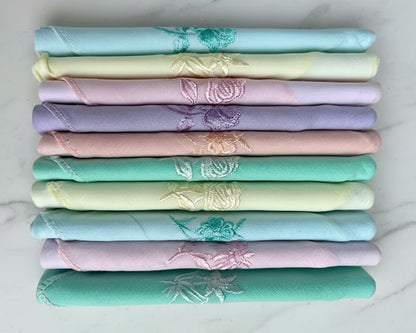 Stack of folded fabric swatches in pastel colors with floral patterns on a white background