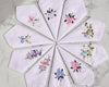 Set of embroidered handkerchiefs arranged in a circular pattern on a marble surface.