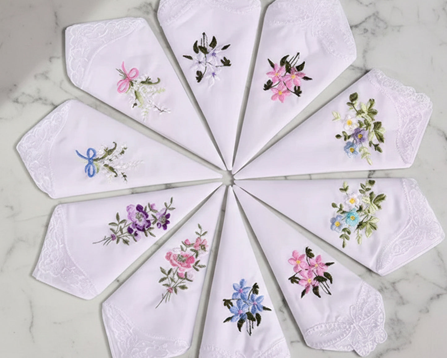 Set of embroidered handkerchiefs arranged in a circular pattern on a marble surface.