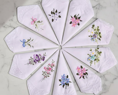 Set of embroidered handkerchiefs arranged in a circular pattern on a marble surface.