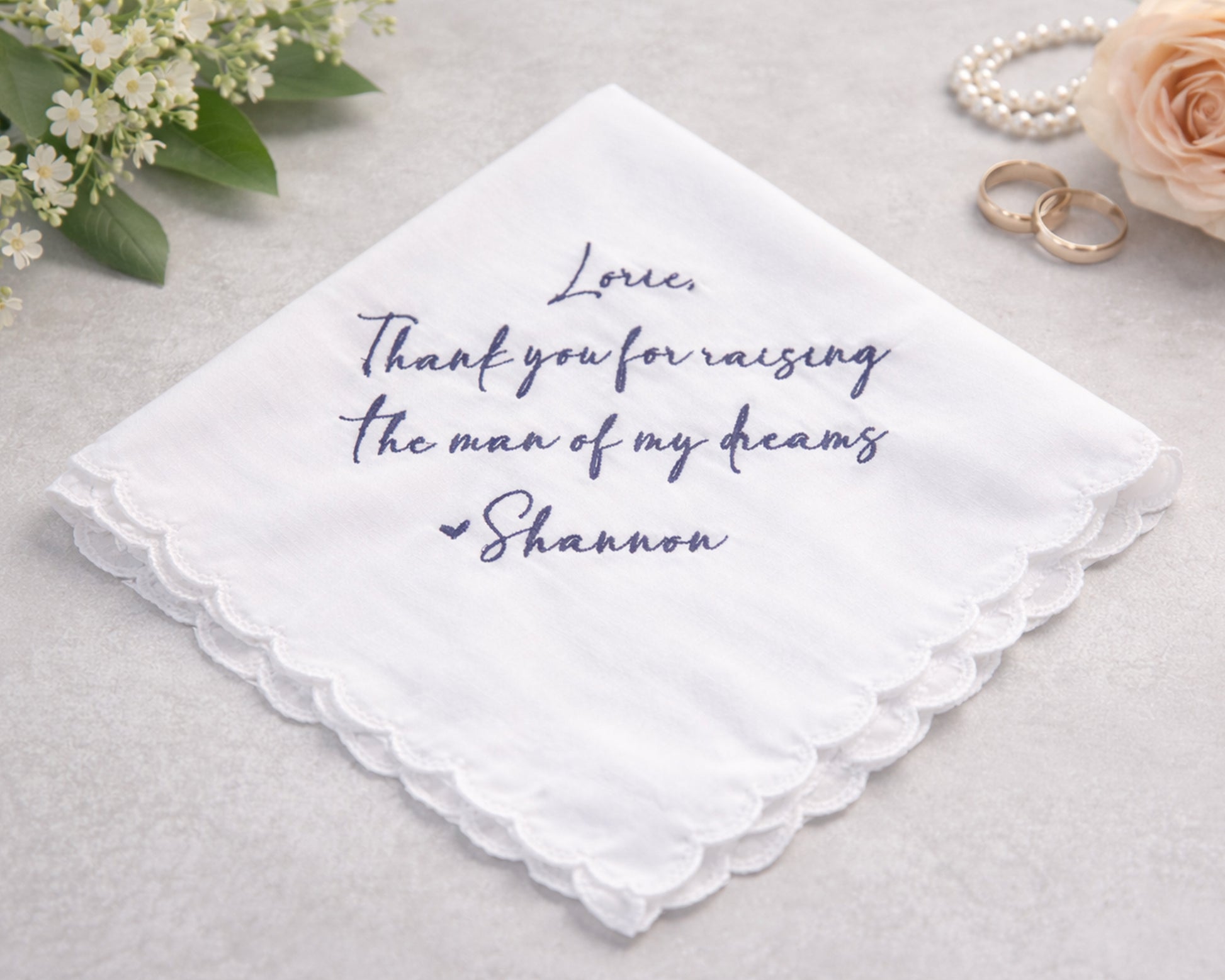White handkerchief with purple text on a light gray background with flowers and rings.