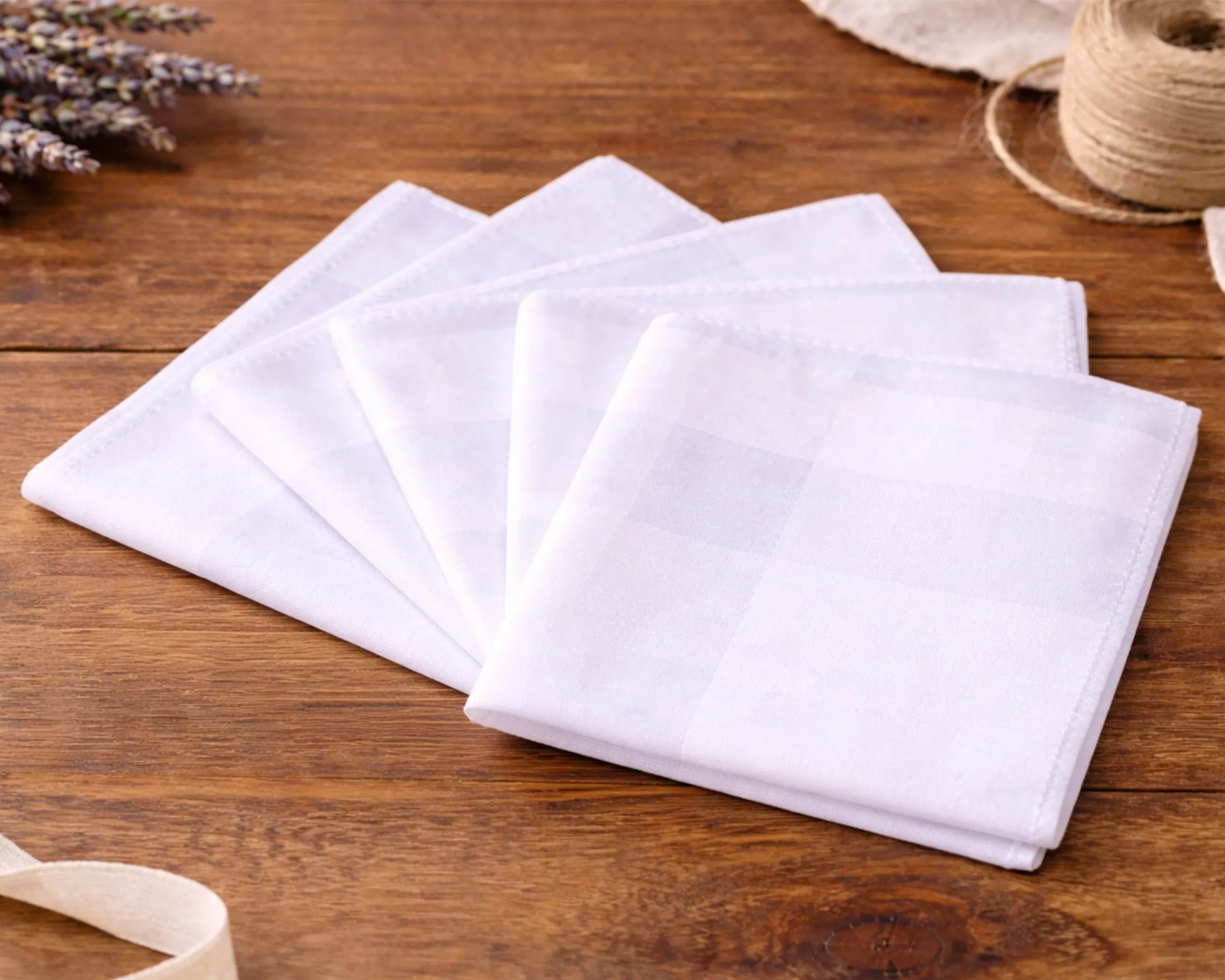 White fabric hanky on a wooden surface with lavender and twine in the background