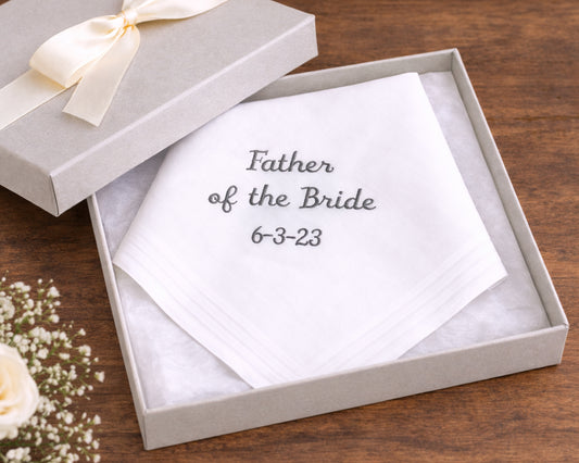 White handkerchief with 'Father of the Bride' text in a gift box on a wooden surface.