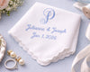 White handkerchief with blue embroidery of 'Julianne & Joseph Jan 1, 2026' on a light blue background with wedding accessories.