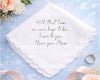 White handkerchief with engraved message on a light blue background with flowers and a ring.