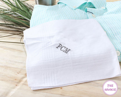 White hankie with 'PCM' monogram on a wooden surface