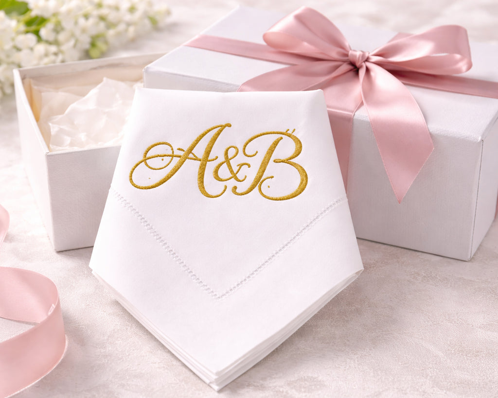 White napkin with 'A&B' in gold, tied with a pink ribbon, on a light background.