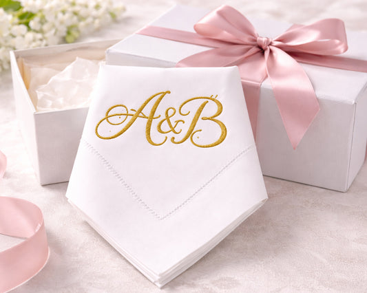 White napkin with 'A&B' in gold, tied with a pink ribbon, on a light background.