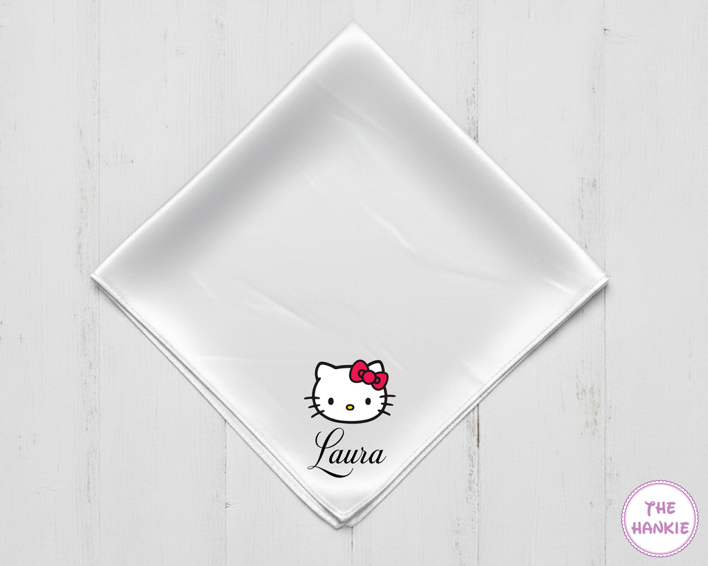 White napkin with Hello Kitty logo and 'Laura' text on a light wooden surface, branded 'The Hankie'.