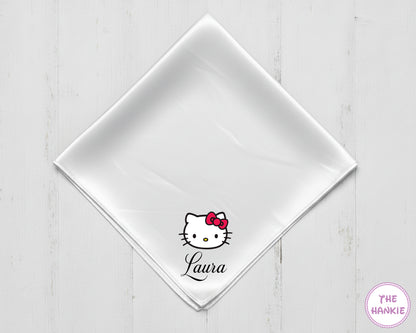 White napkin with Hello Kitty logo and 'Laura' text on a light wooden surface, branded 'The Hankie'.