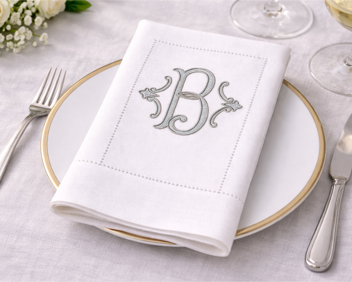 White napkin with monogram 'B' on a table setting with cutlery and glasses.