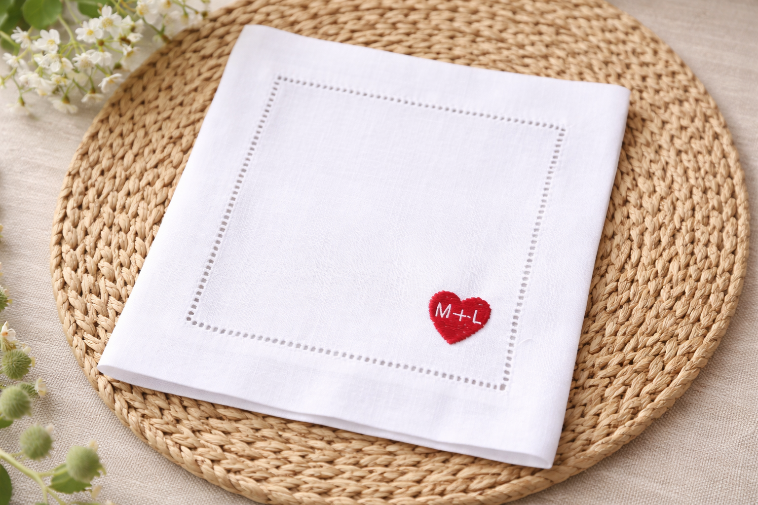 White napkin with red heart and initials on a woven placemat