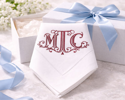 White napkin with red monogram 'MTC' in a box with a blue ribbon