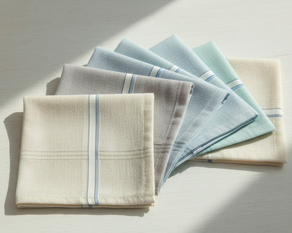 Set of folded napkins in beige, blue, and gray on a light surface