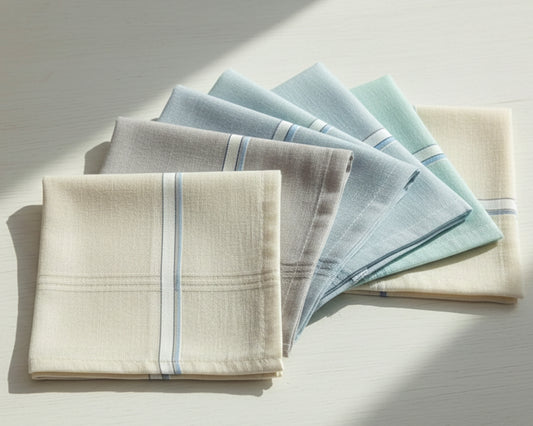 Set of folded napkins in beige, blue, and gray on a light surface