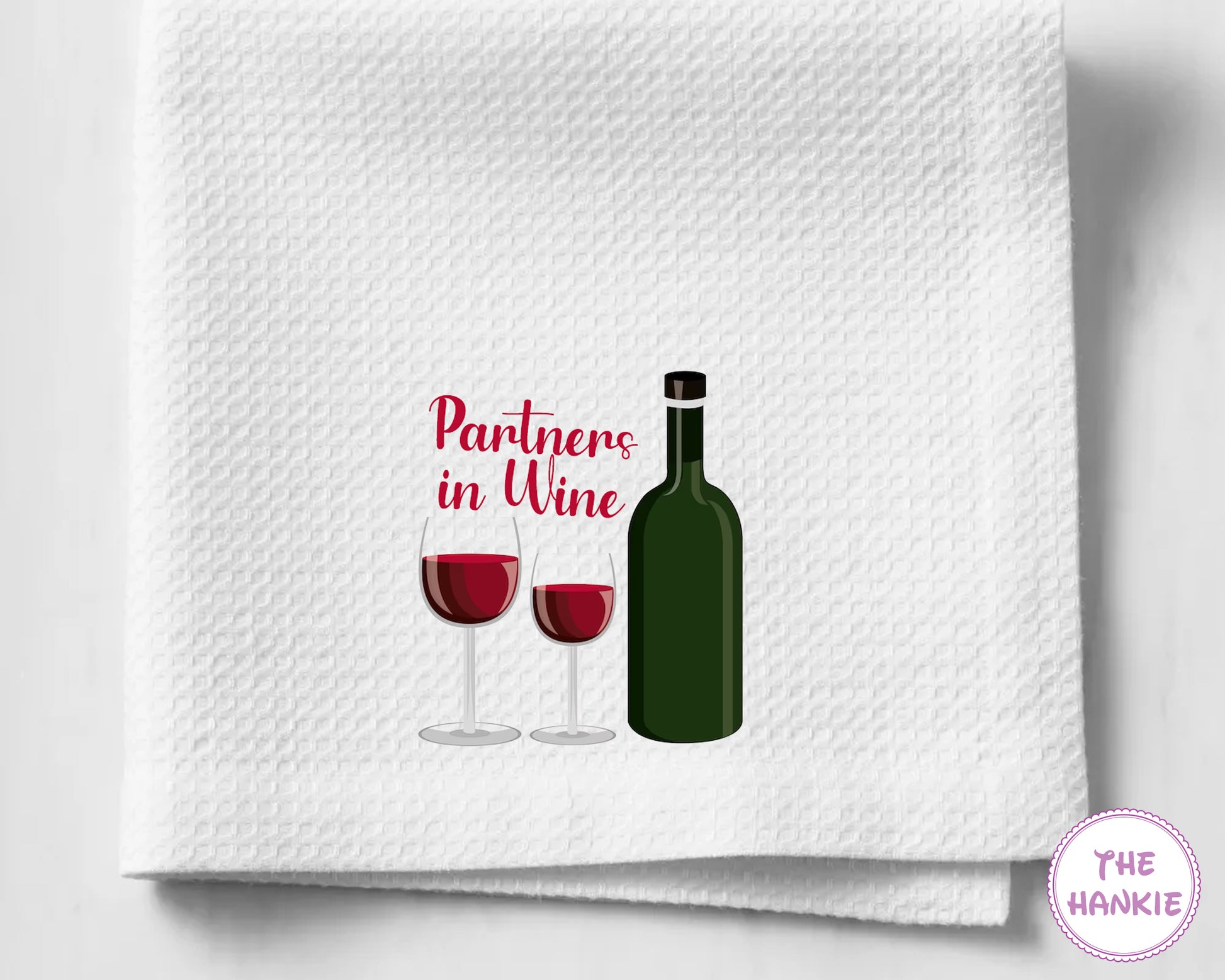White towel with wine bottle and glasses design and 'Partners in Wine' text on a white background.