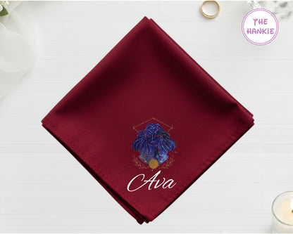 A midnight burgundy cotton handkerchief customized with the name "Ava" below a mystical indigo and gold Virgo goddess design.