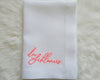 Overhead view of a custom hemstitch linen napkin on a white dinner plate, styled for a modern formal event or wedding