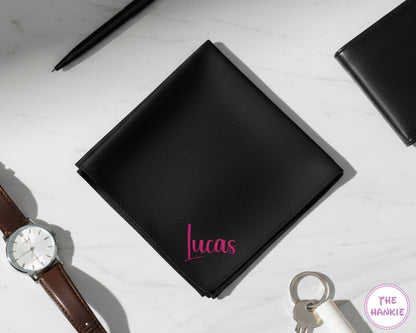 A bespoke black cotton handkerchief showcasing the name "Lucas" in a vibrant pink glitter vinyl script.