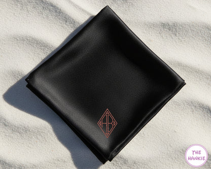 A bespoke black satin handkerchief showcasing a rose copper vinyl "AB" monogram inside a modern geometric diamond frame.