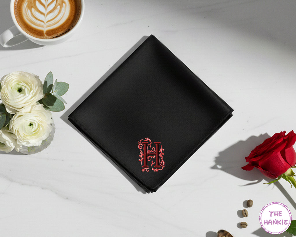 A premium black cotton handkerchief featuring a large, ornate red embroidered initial "H" with decorative floral flourishes.