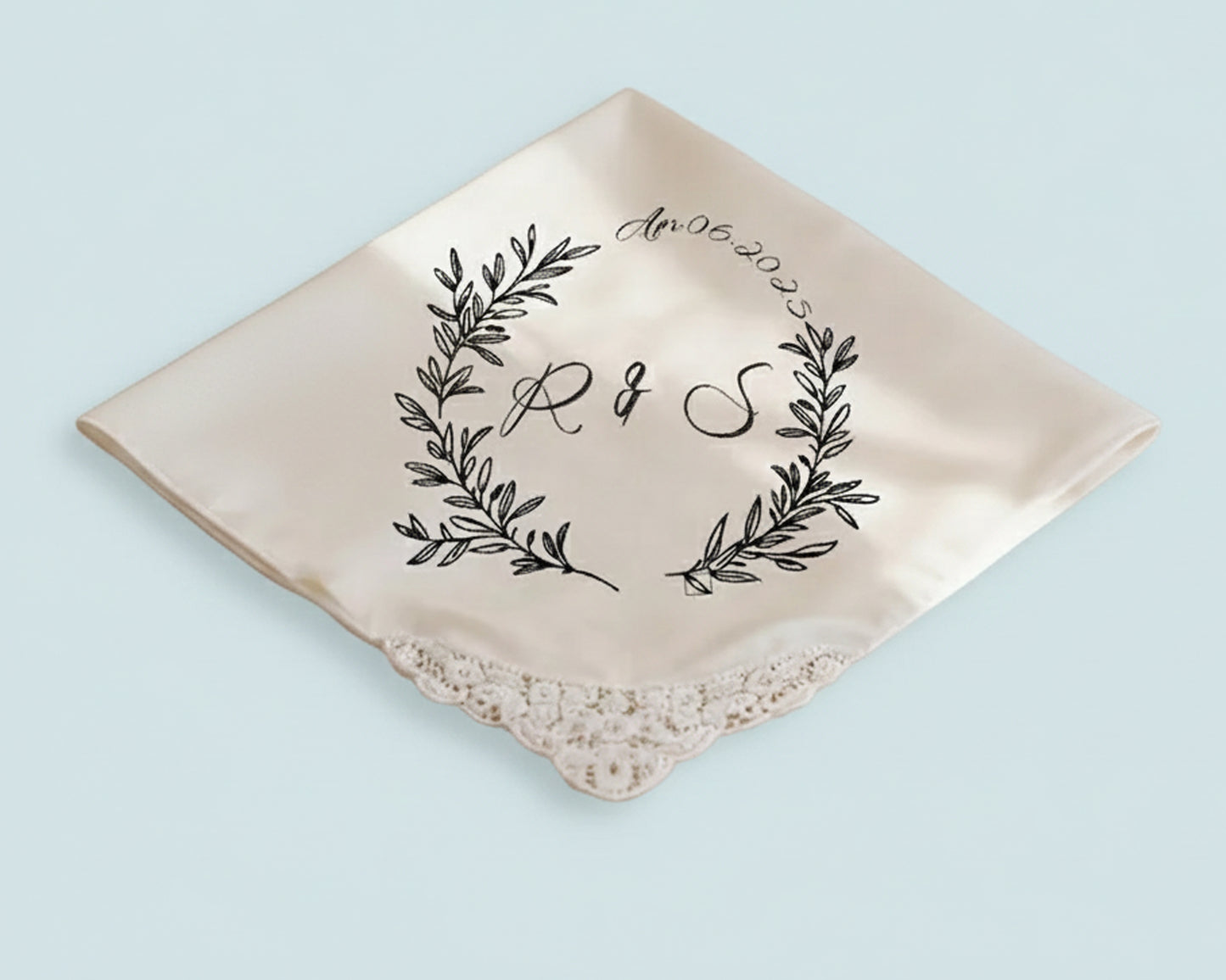 White cotton dinner napkin with a soft blue embroidered ribbon bow and a personalized letter B initial