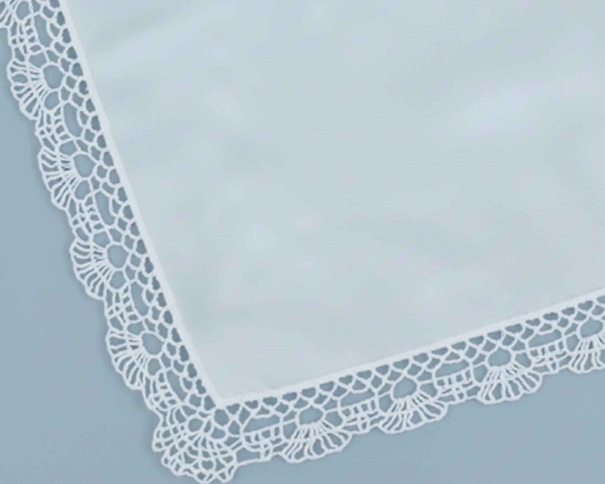 Close up corner view of a soft sky blue cotton handkerchief with a scalloped lace border.