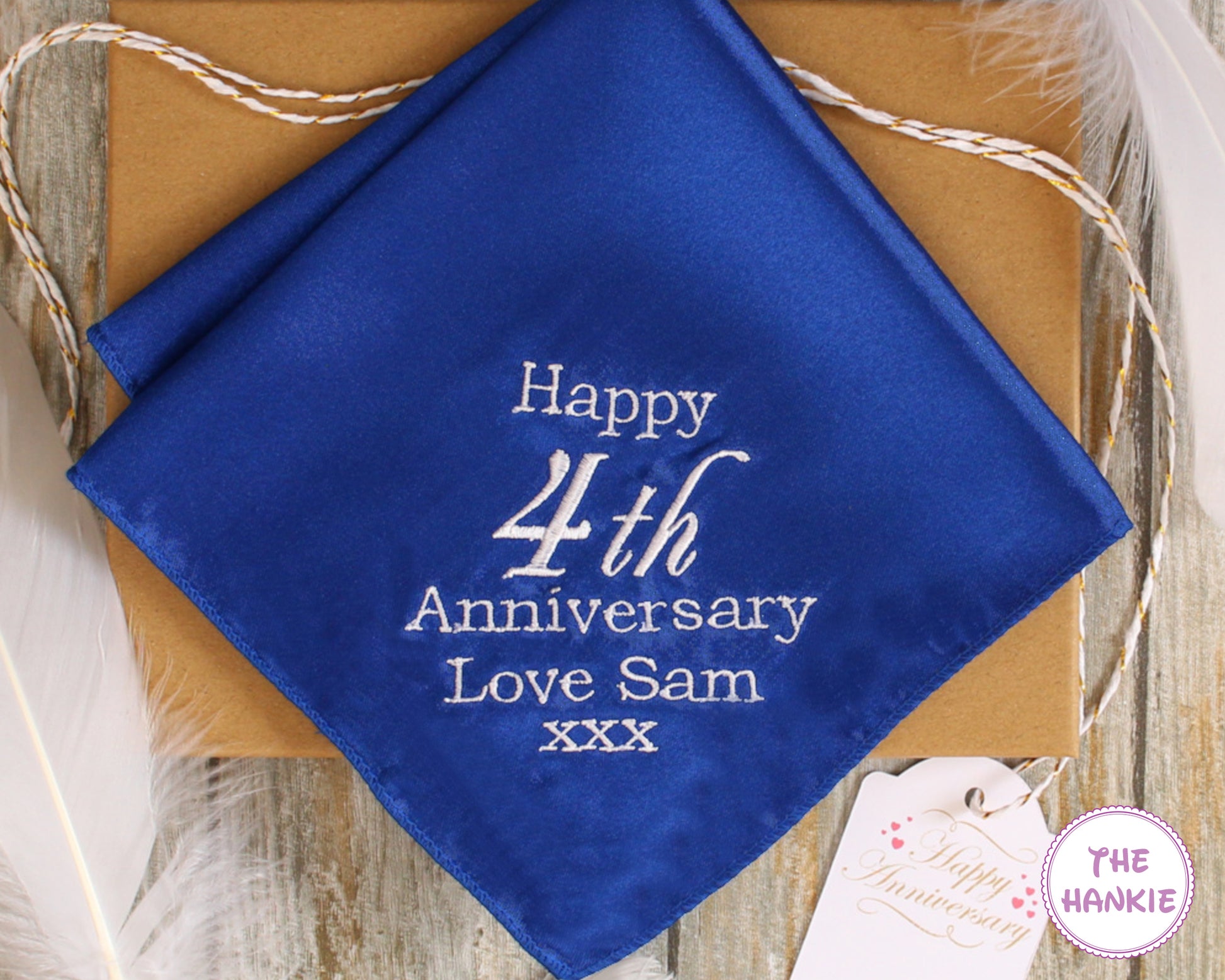 Blue handkerchief with 'Happy 4th Anniversary Love Sam xxx' text on a wooden surface.