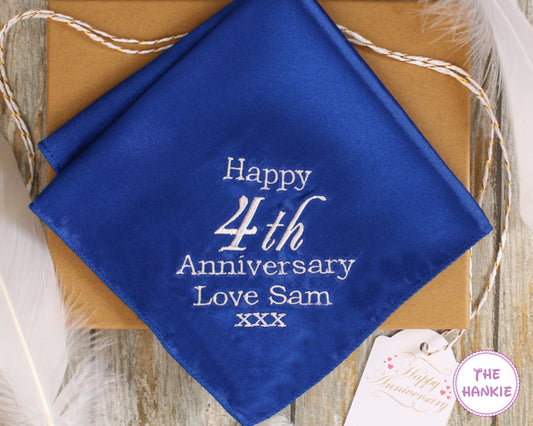 Blue handkerchief with 'Happy 4th Anniversary Love Sam xxx' text on a wooden surface.