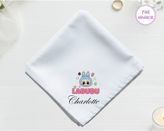 A crisp white cotton handkerchief featuring a colorful machine-embroidered character icon and the name "Charlotte" in black script.