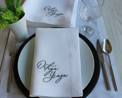 Custom name embroidery with a soft blue ribbon bow motif on a white hemstitched cotton cloth