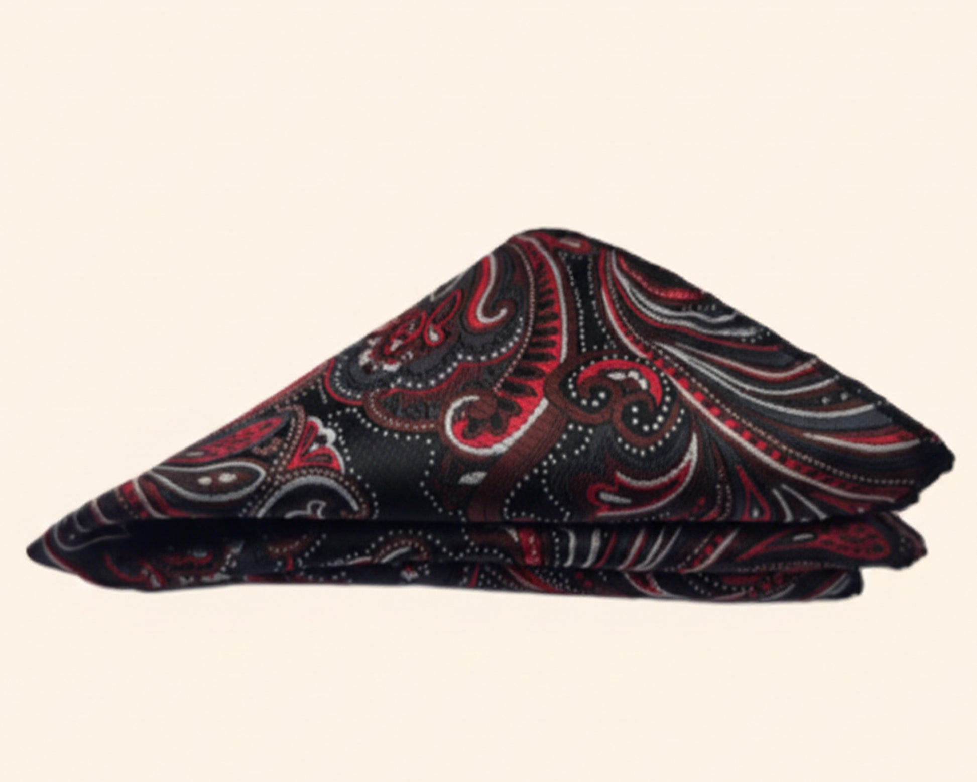 Close up of a crimson paisley silk pocket square styled in a classic puff fold showing the intricate silk texture.