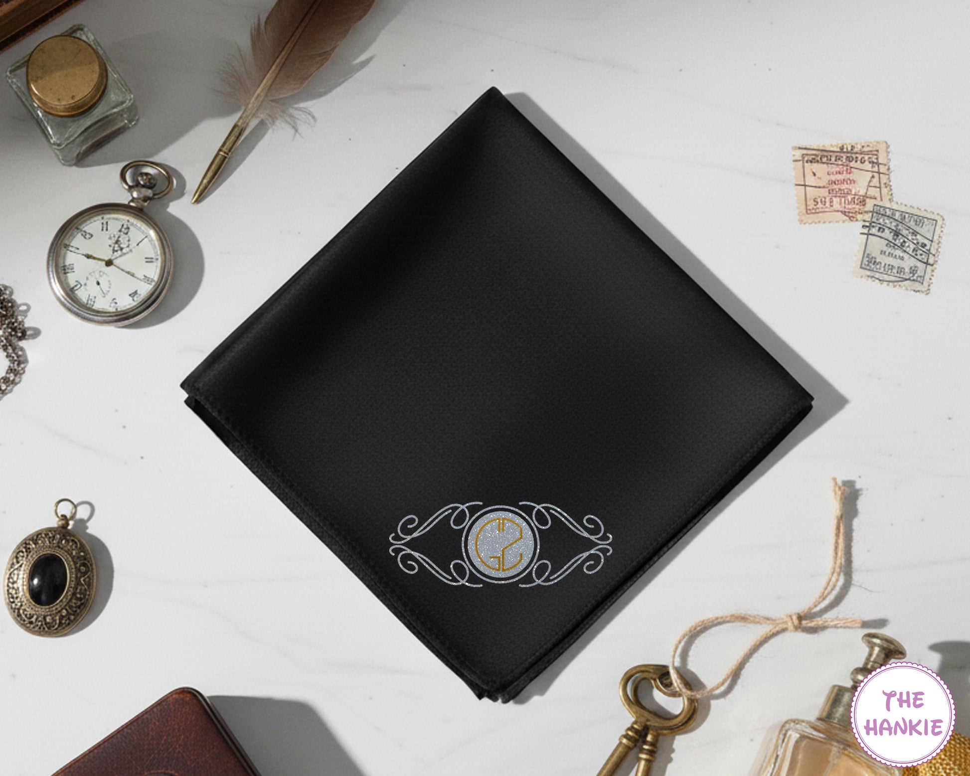 A bespoke black cotton handkerchief showcasing a high-definition silver and gold vinyl crest monogram on a vintage-styled background.