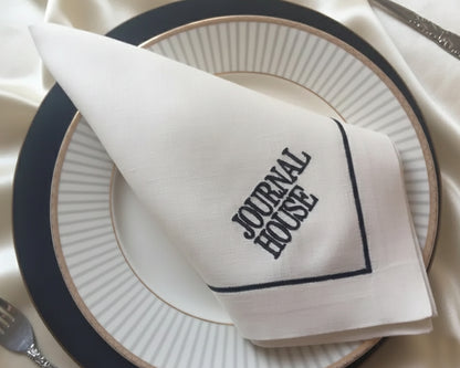 Napkin with 'Journal House' text on a white plate with black rim
