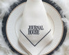 White napkin with 'Journal House' text on a black and white plate with feathered background