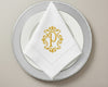 Custom embroidered cotton napkin featuring gold ornate P monogram, styled in triangle fold on formal table setting