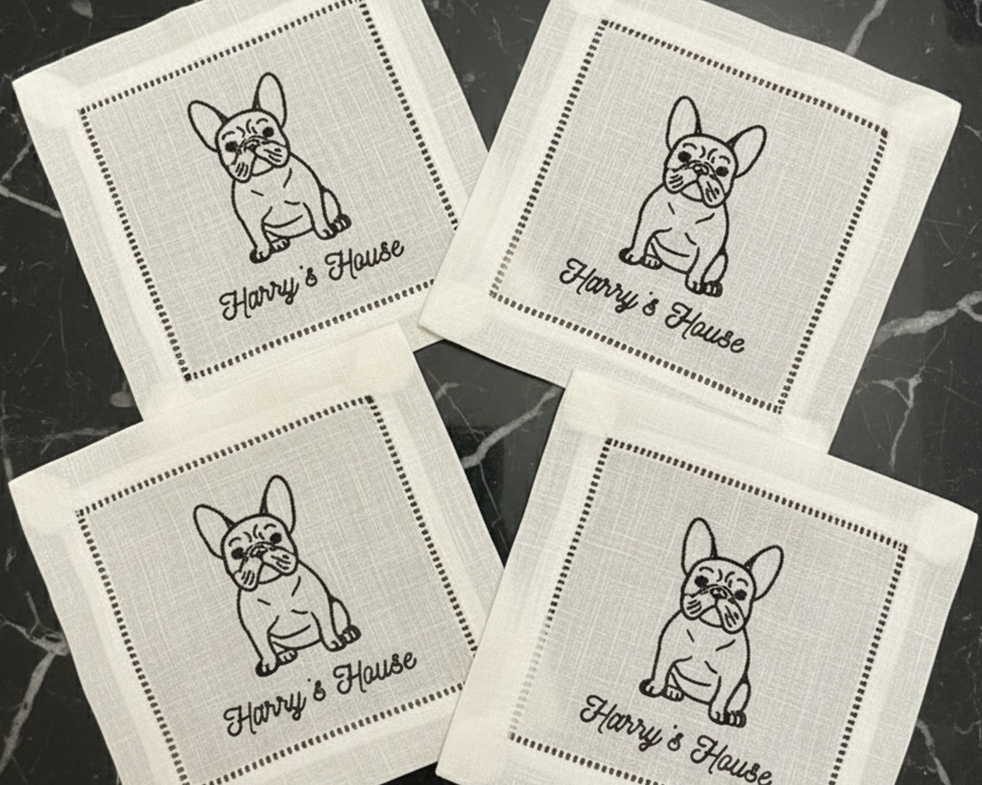 A close-up of a premium white cotton beverage coaster with a hemstitch border, personalized with a detailed machine-embroidered dog illustration and cocktail icon.