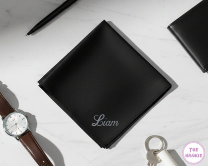 A black cotton pocket square featuring the name "Liam" in a modern silver glitter vinyl script.