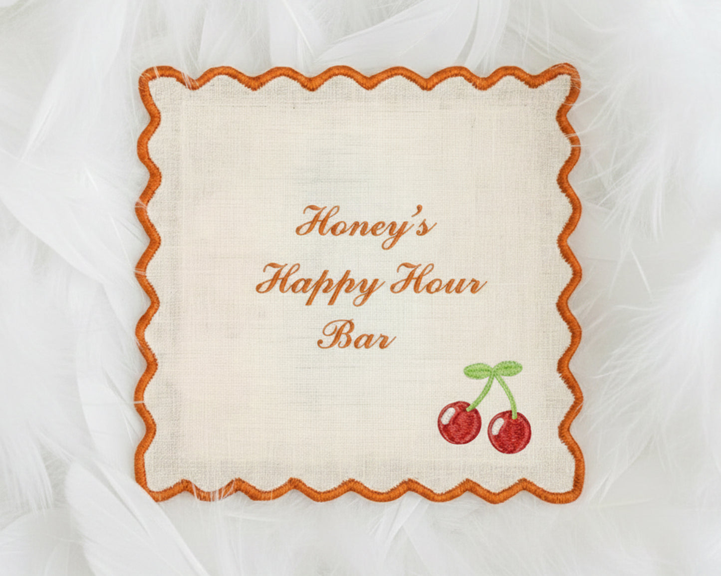 A collection of four light blue cotton cocktail napkins with white scalloped edges, each featuring personalized name embroidery and a pet icon.