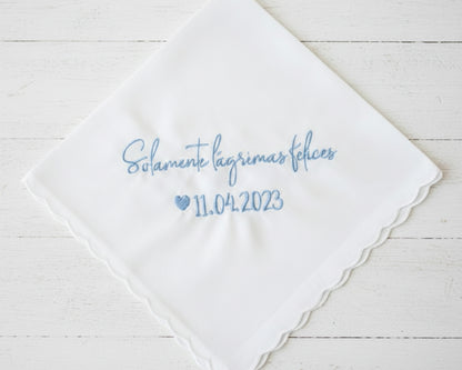 Personalized Spanish wedding handkerchief with a heart and the phrase "Solamente lágrimas felices" in light blue embroidery, shown on soft pink silk.
