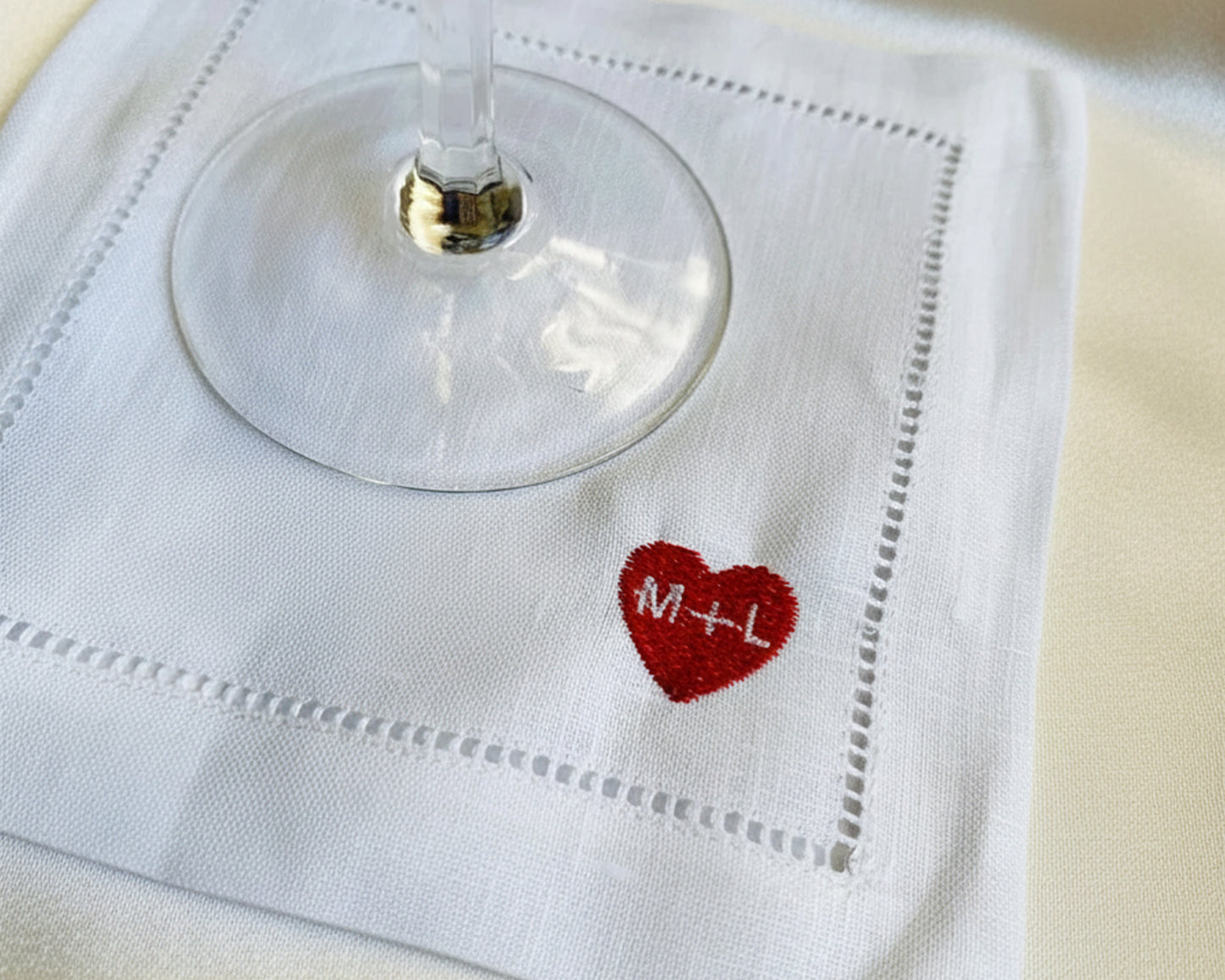 White napkin with a red heart and initials 'M' and 'L', holding a glass.